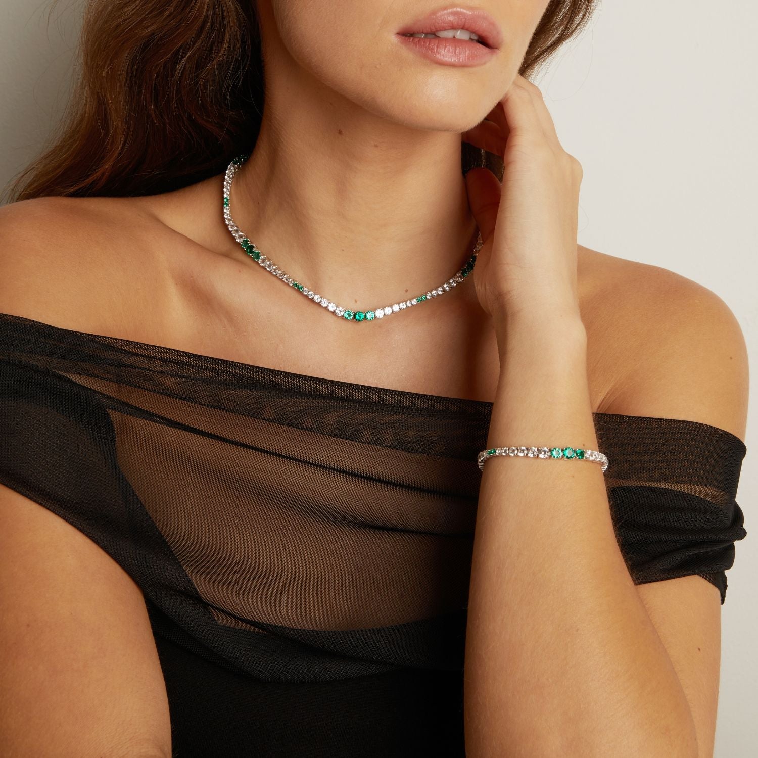 Woman wearing a green and silver beaded necklace and bracelet against a neutral background