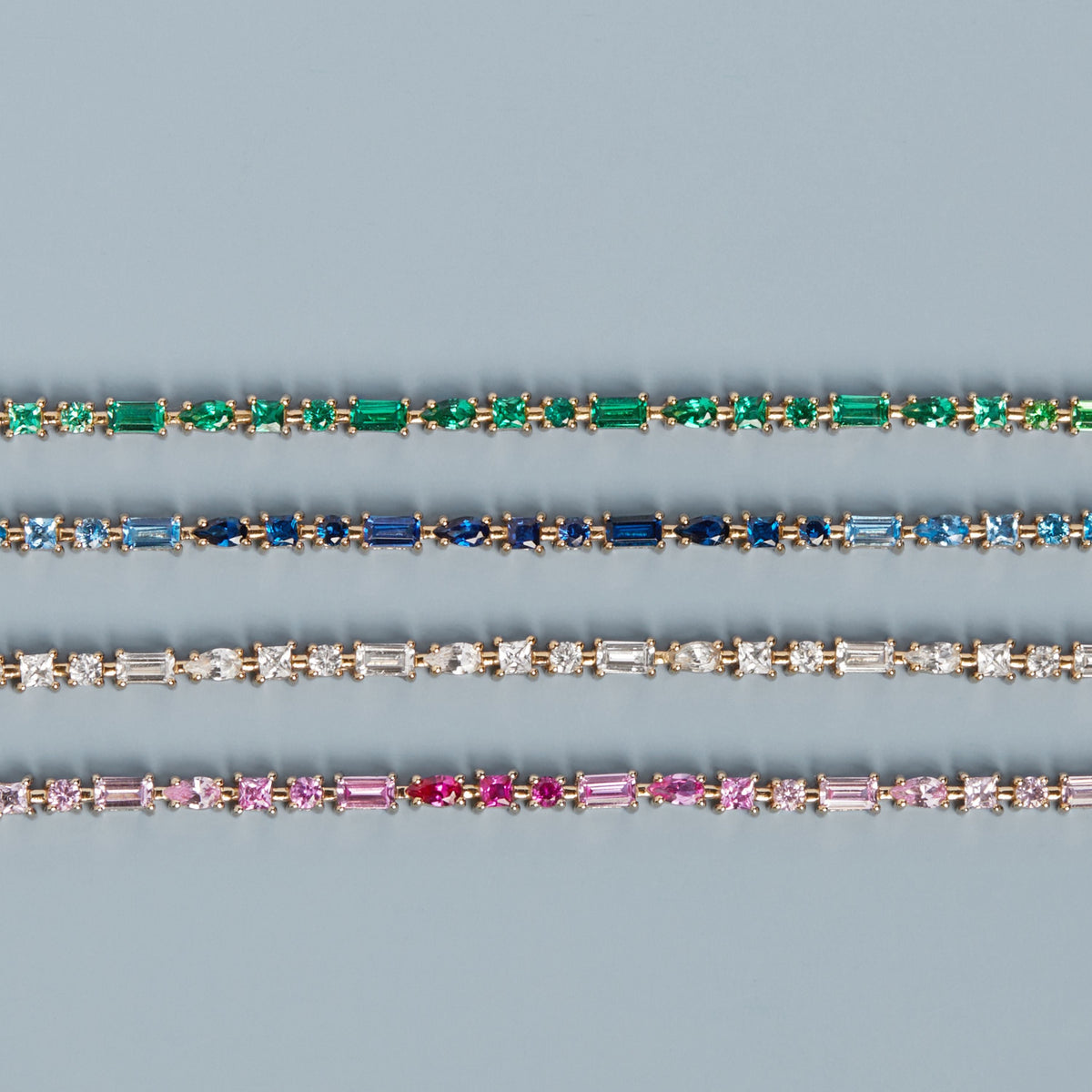 Model. Three diamond bracelets with different colored gemstones on a blue background