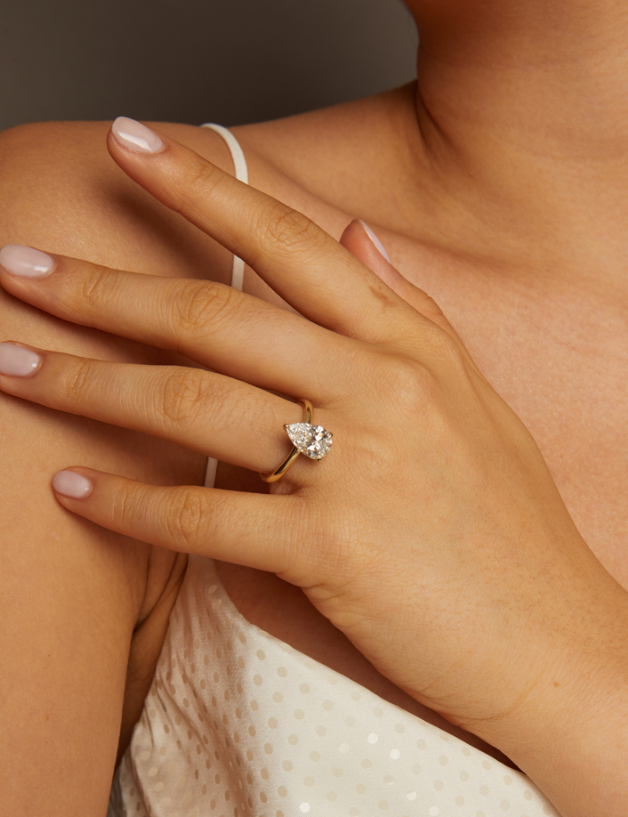 Hand wearing a diamond ring on a neutral background