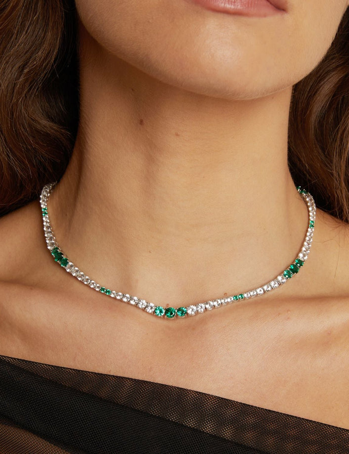  Close-up of a woman wearing a silver necklace with green gemstones.