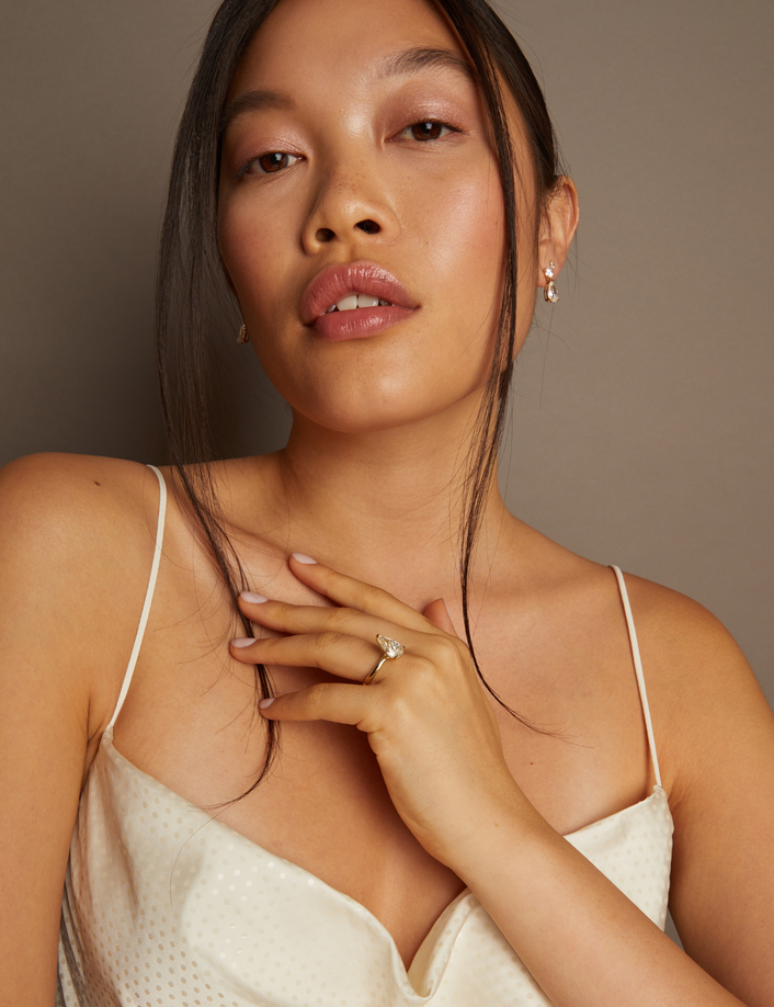 Model. Woman wearing a beige dress against a brown background