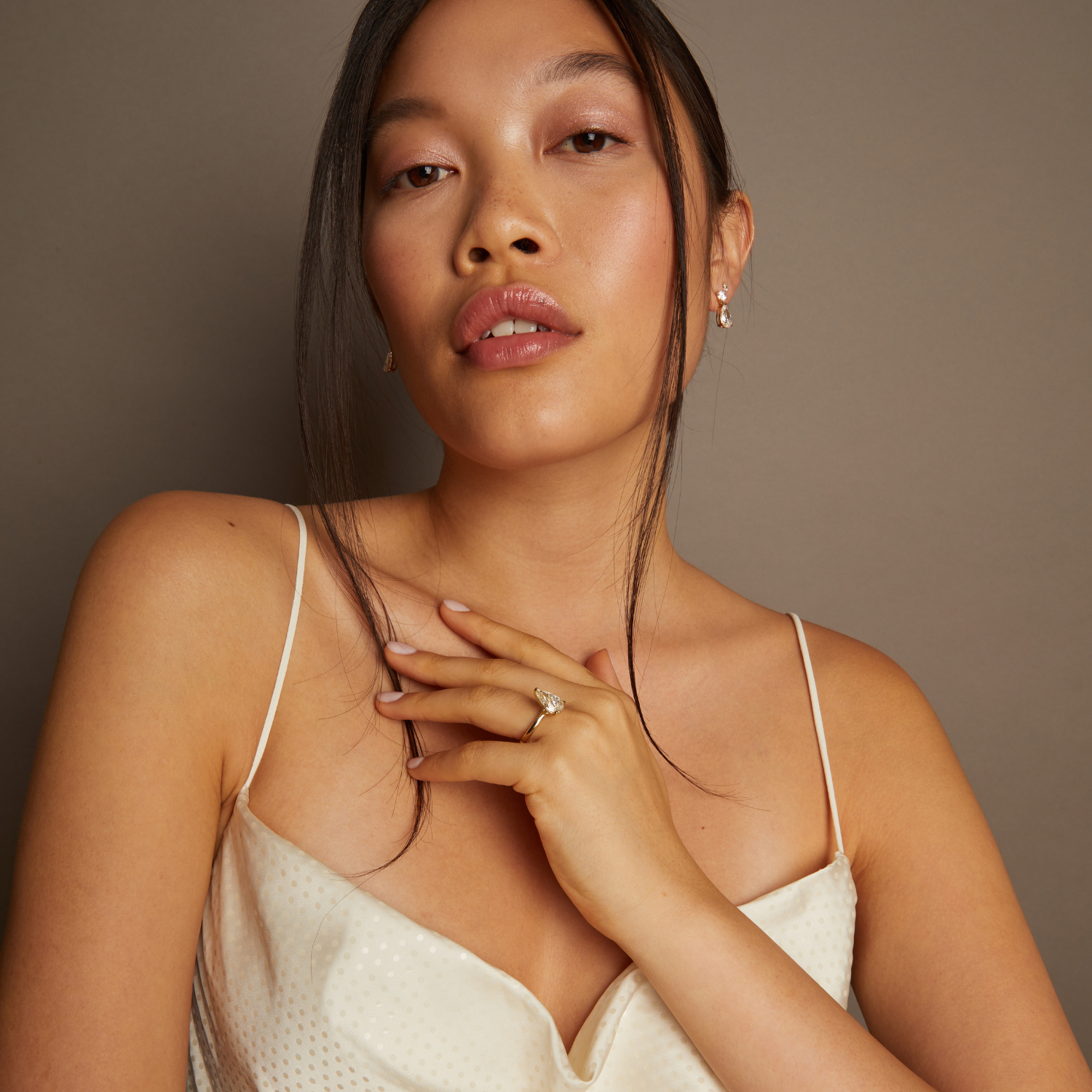 Model. Woman wearing a beige dress against a brown background