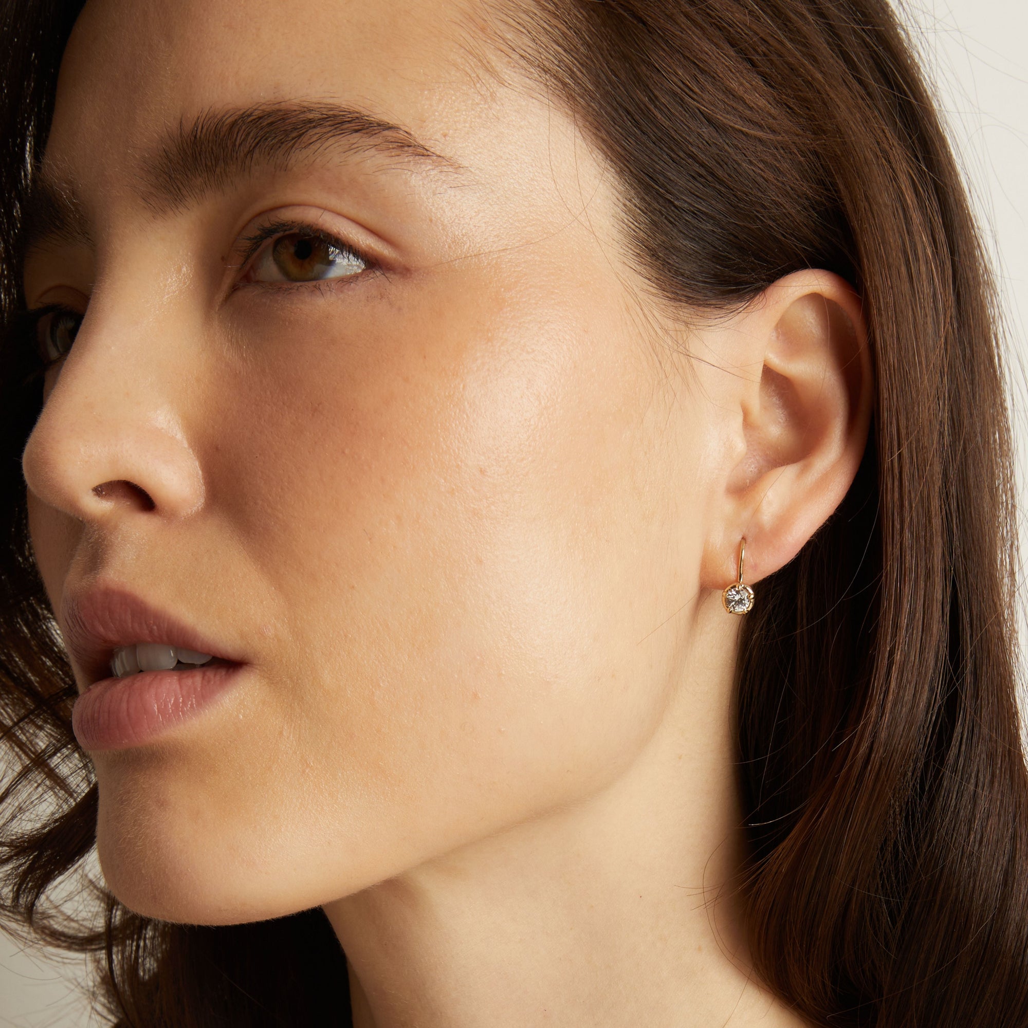 Model. Close-up of a woman wearing a diamond earring with a neutral background