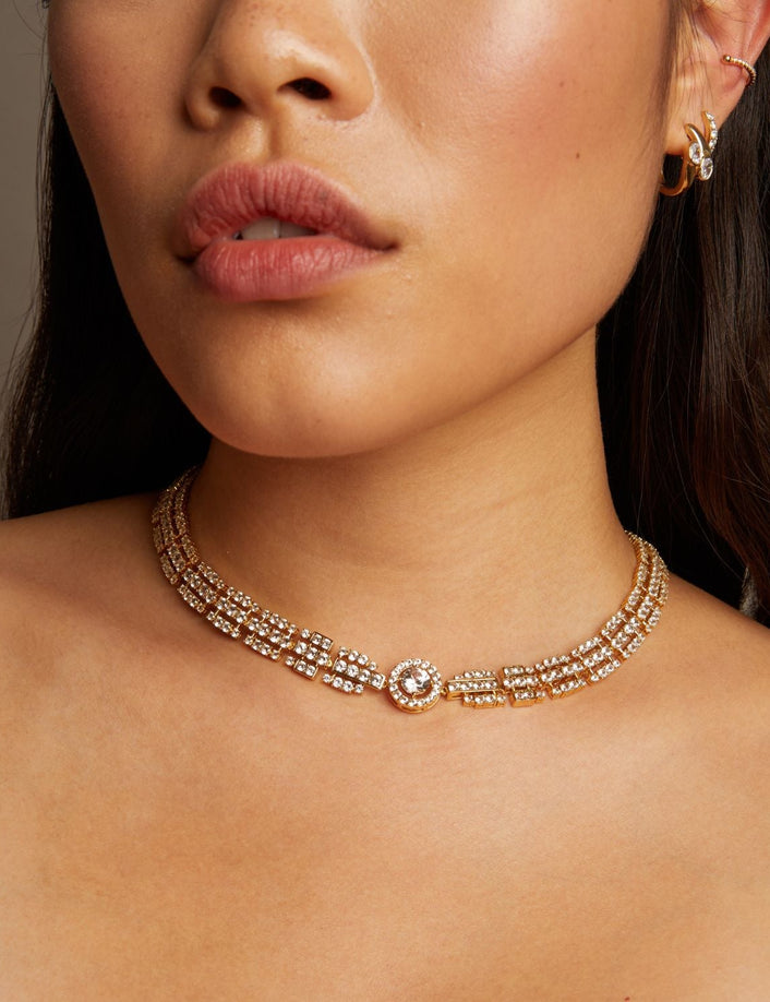 Close-up of a woman wearing a gold necklace with a neutral background