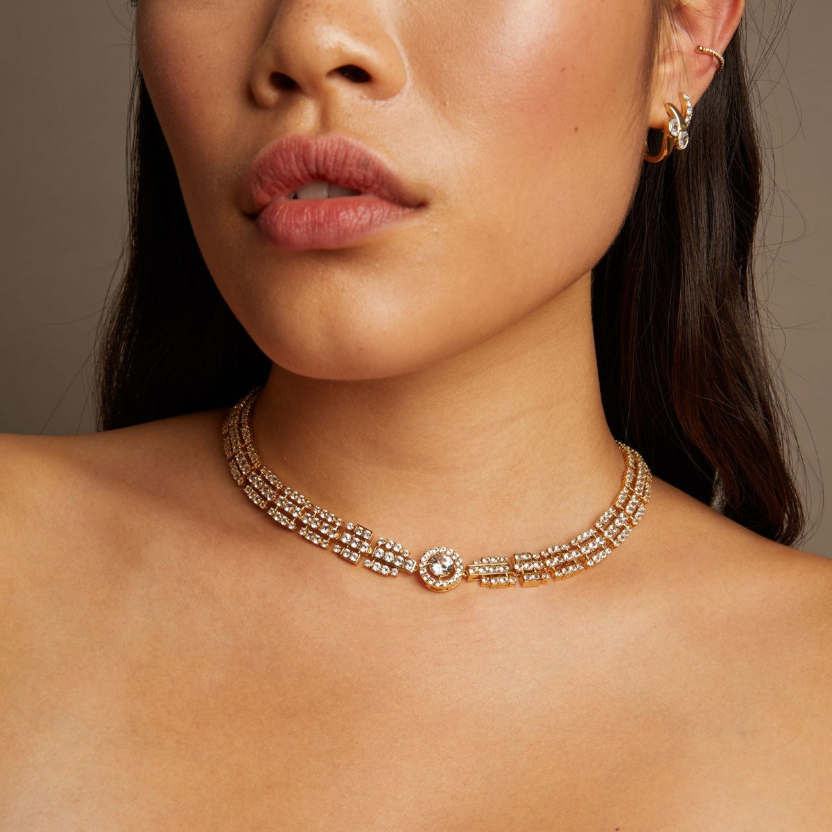 Close-up of a woman wearing a gold necklace with a neutral background