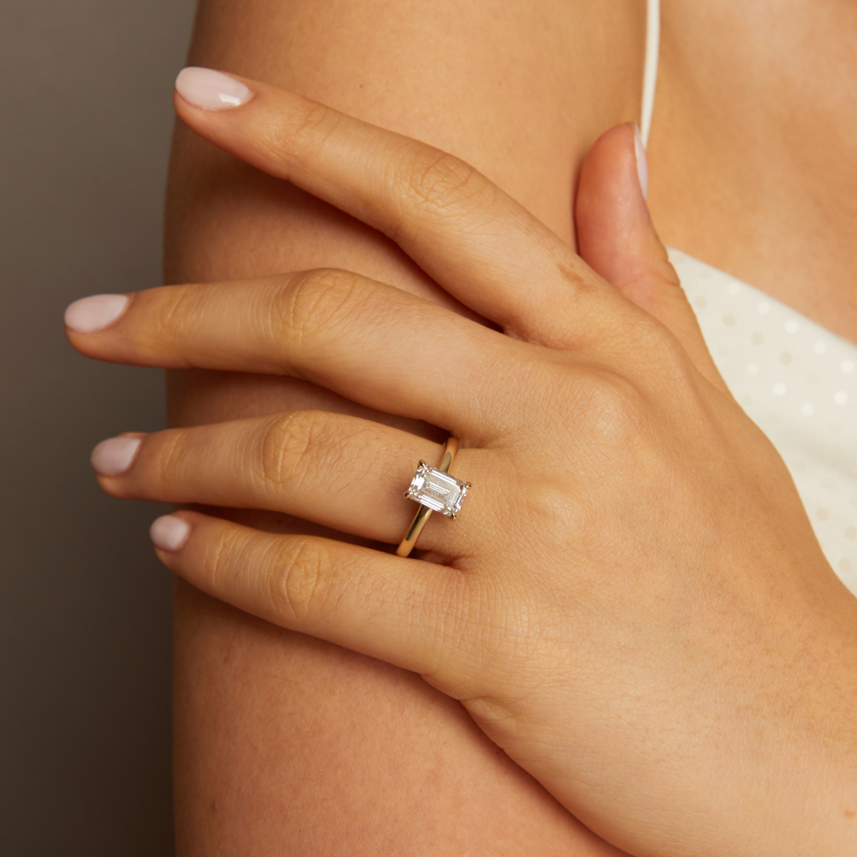 Model. Close-up of a hand wearing a diamond ring on a neutral background