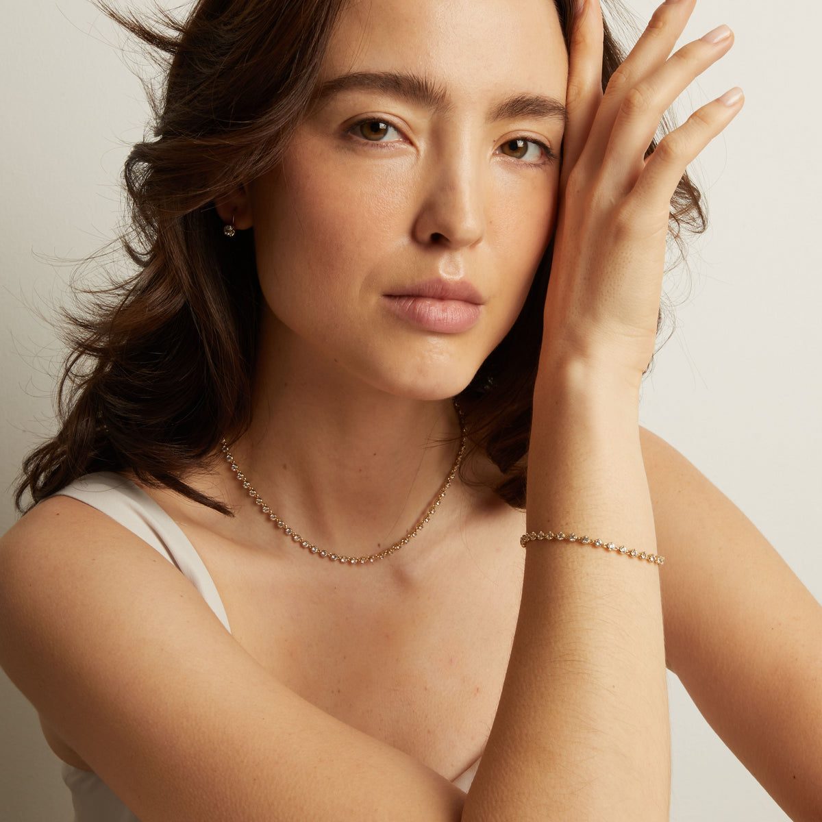 Model Woman wearing a gold necklace and bracelet against a neutral background