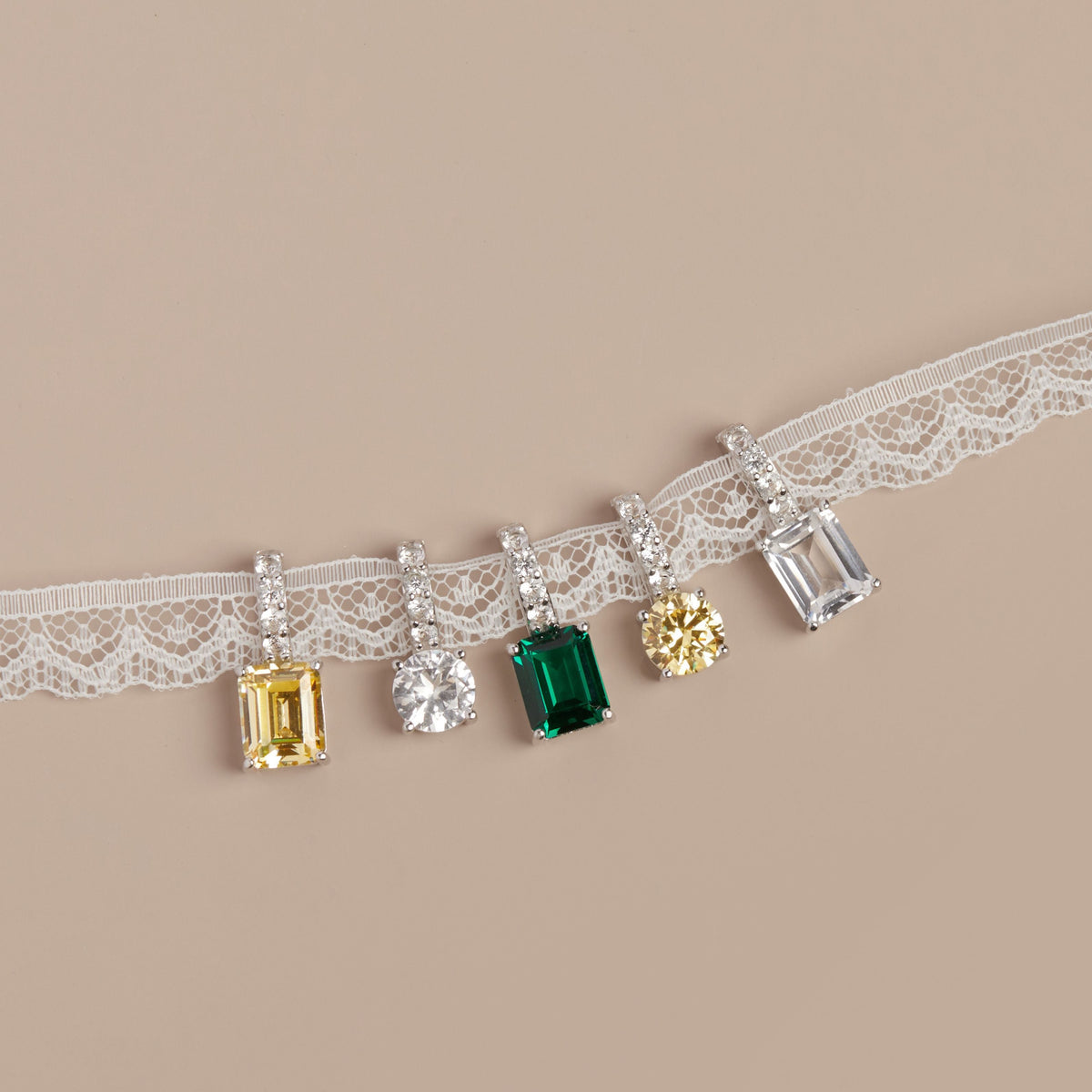 Model. Lace ribbon with various gemstones pendants on a beige background.