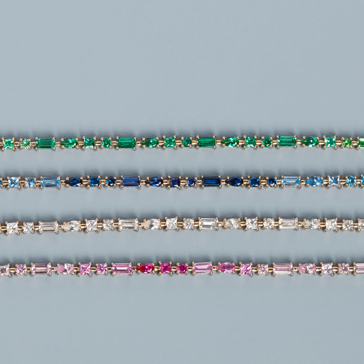 Model. Three diamond bracelets with different colored gemstones on a blue background