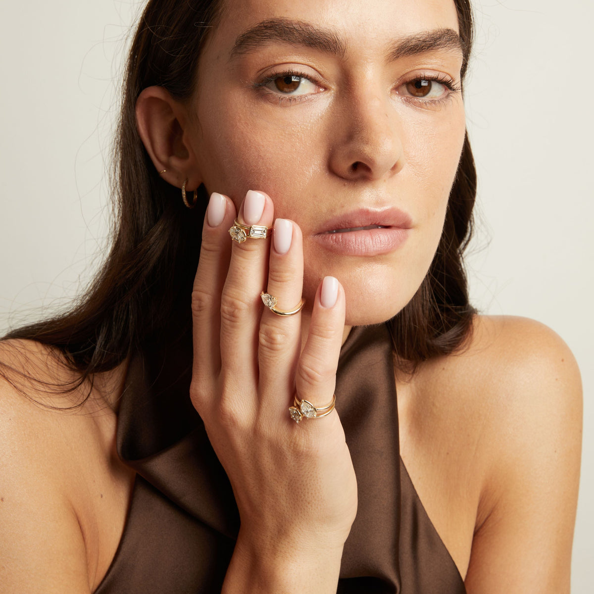 Model. A close-up lifestyle shot of a woman wearing 5 delicate gold diamond rings.