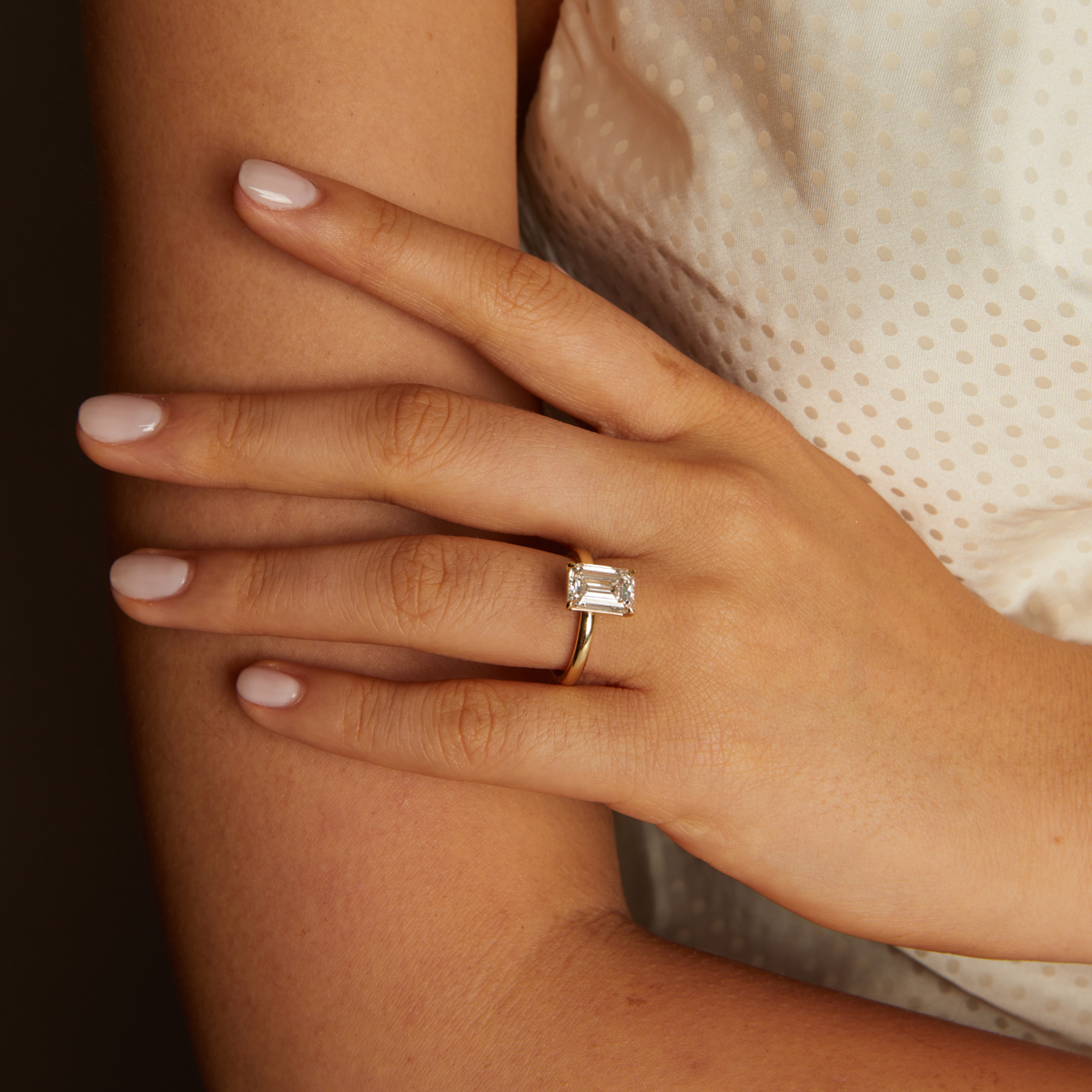 Model. Close-up of a hand wearing a diamond ring on a dark background