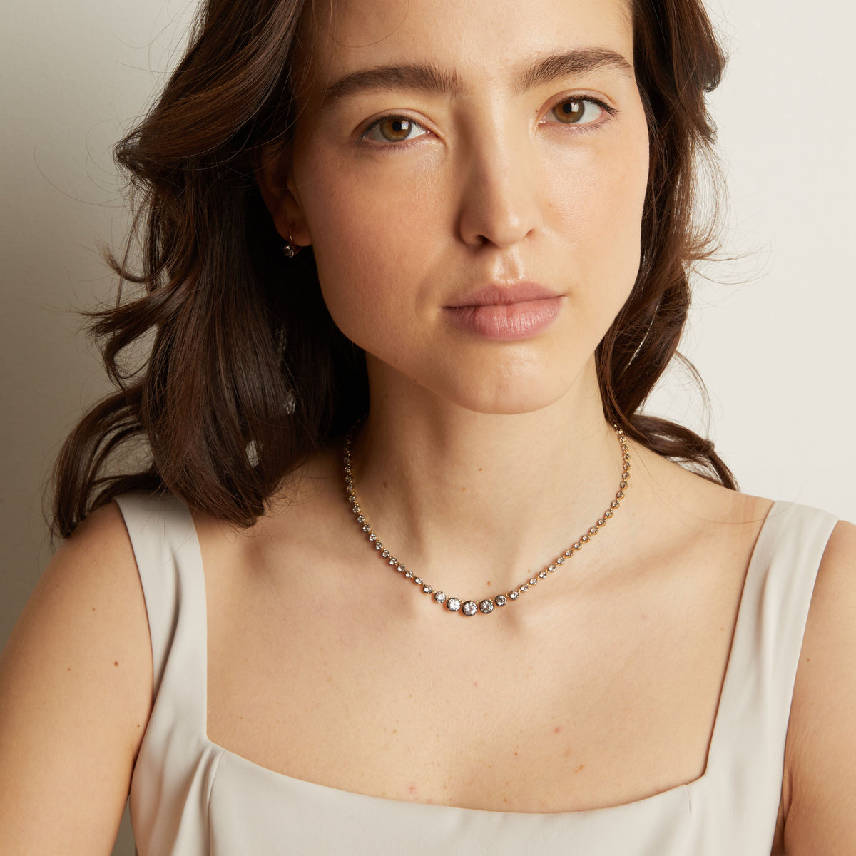 Model. Woman in light top wearing a diamond necklace. 