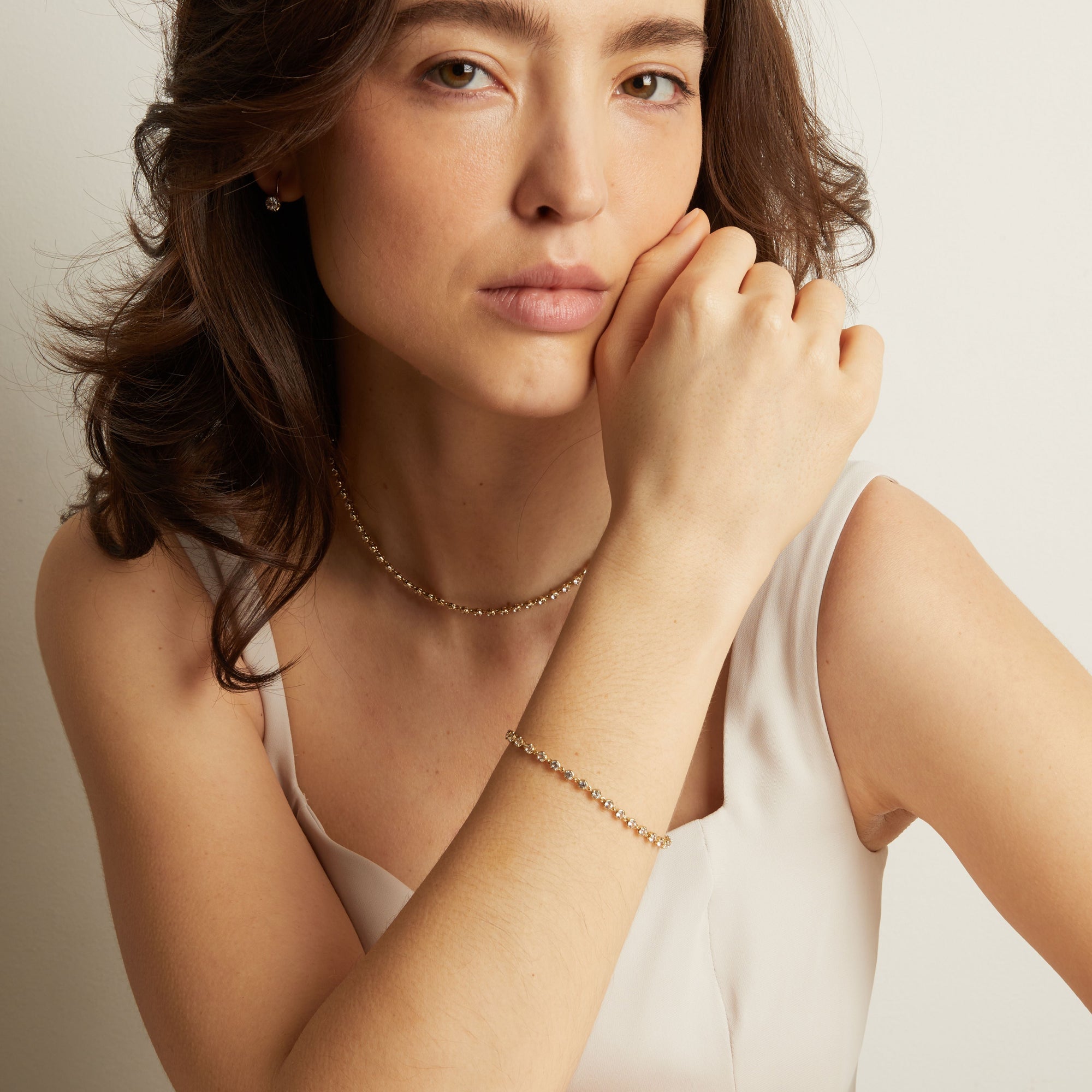Model Woman wearing a delicate gold necklace and bracelet against a neutral background