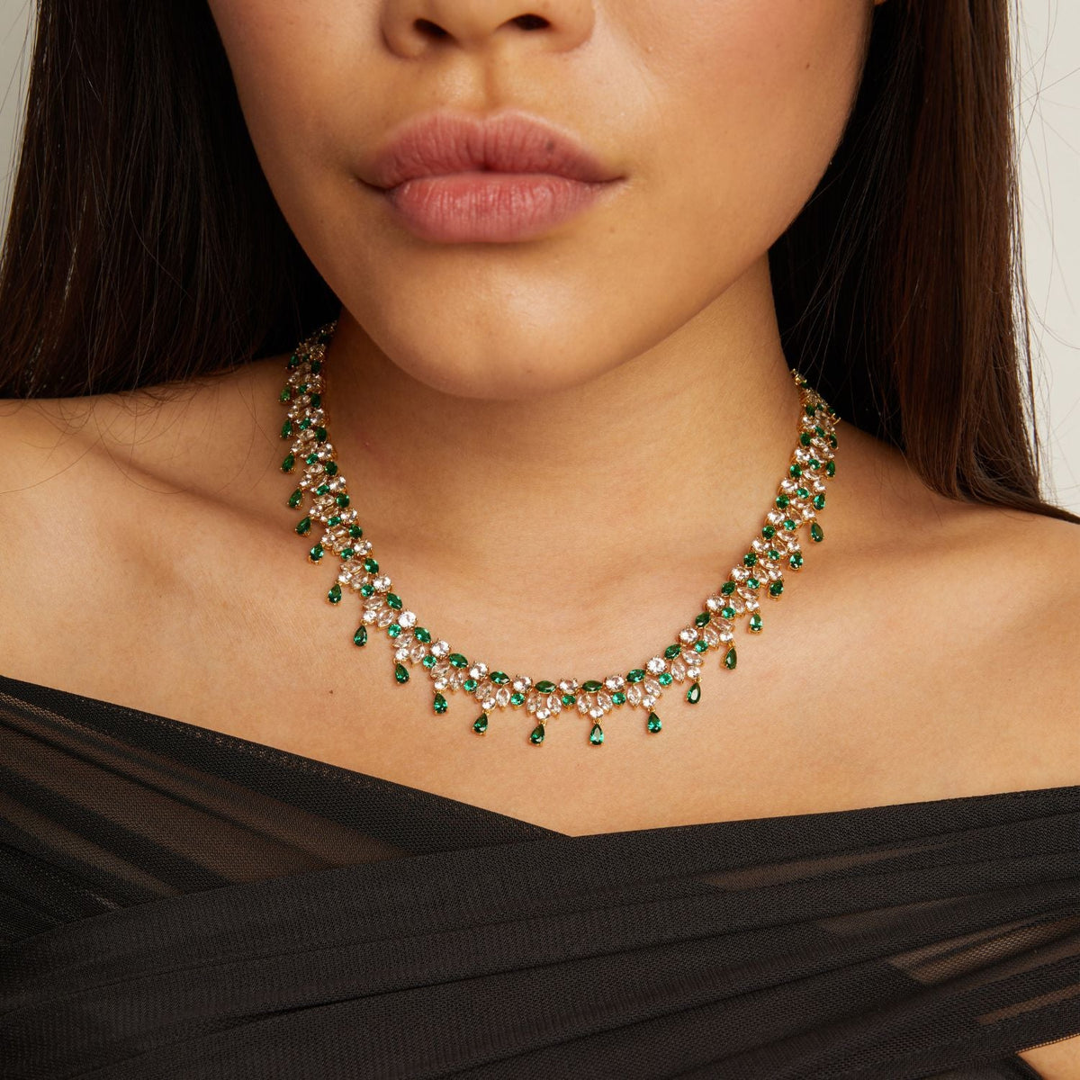 Model. Woman wearing a green gemstone necklace with a black top.