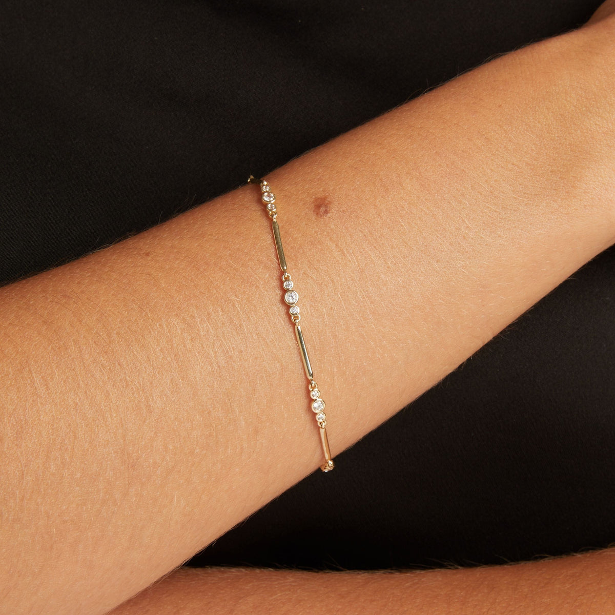 Model. Close up of woman wearing a black shirt with a diamond bar bracelet.