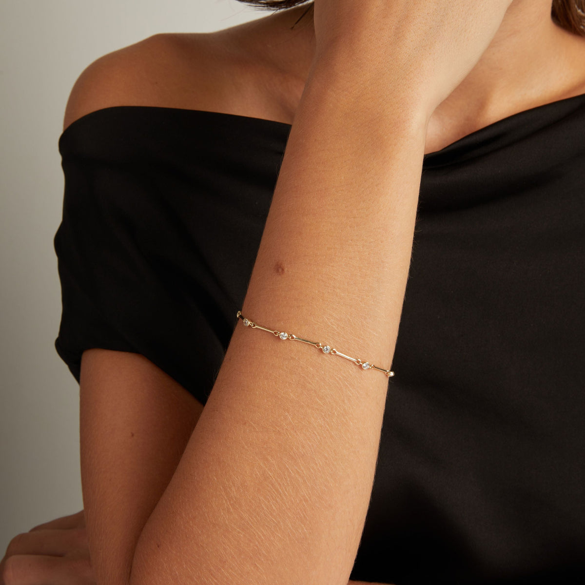 Model. Close up of woman's wrist with a diamond bar bracelet on black shirt. 