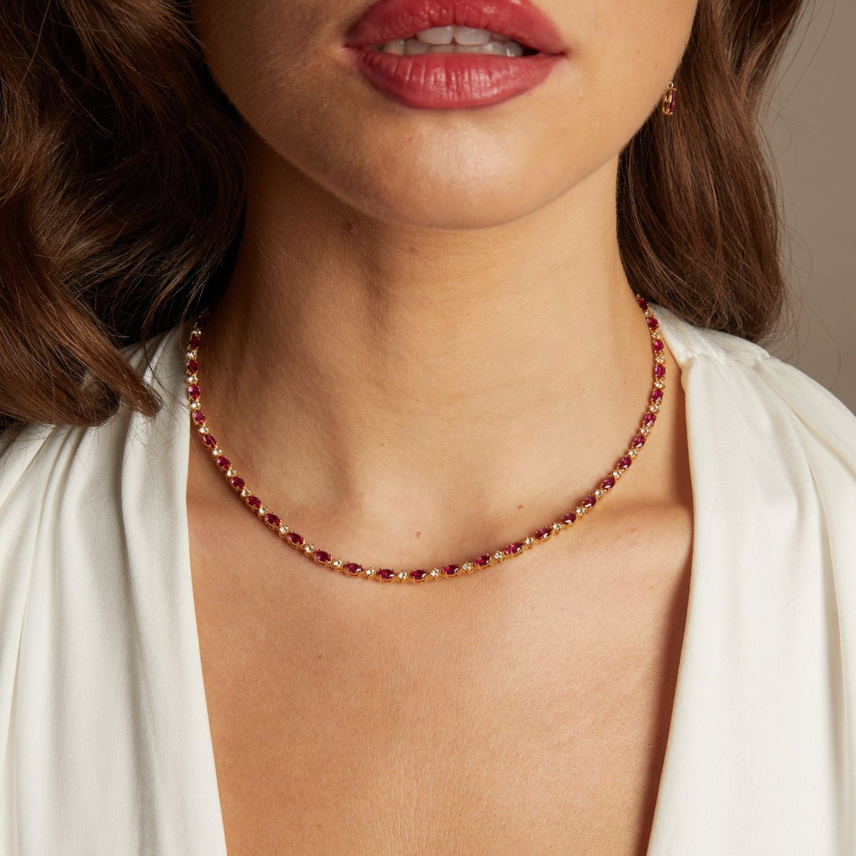 Model. Necklace with red gemstones worn by a person with a neutral background
