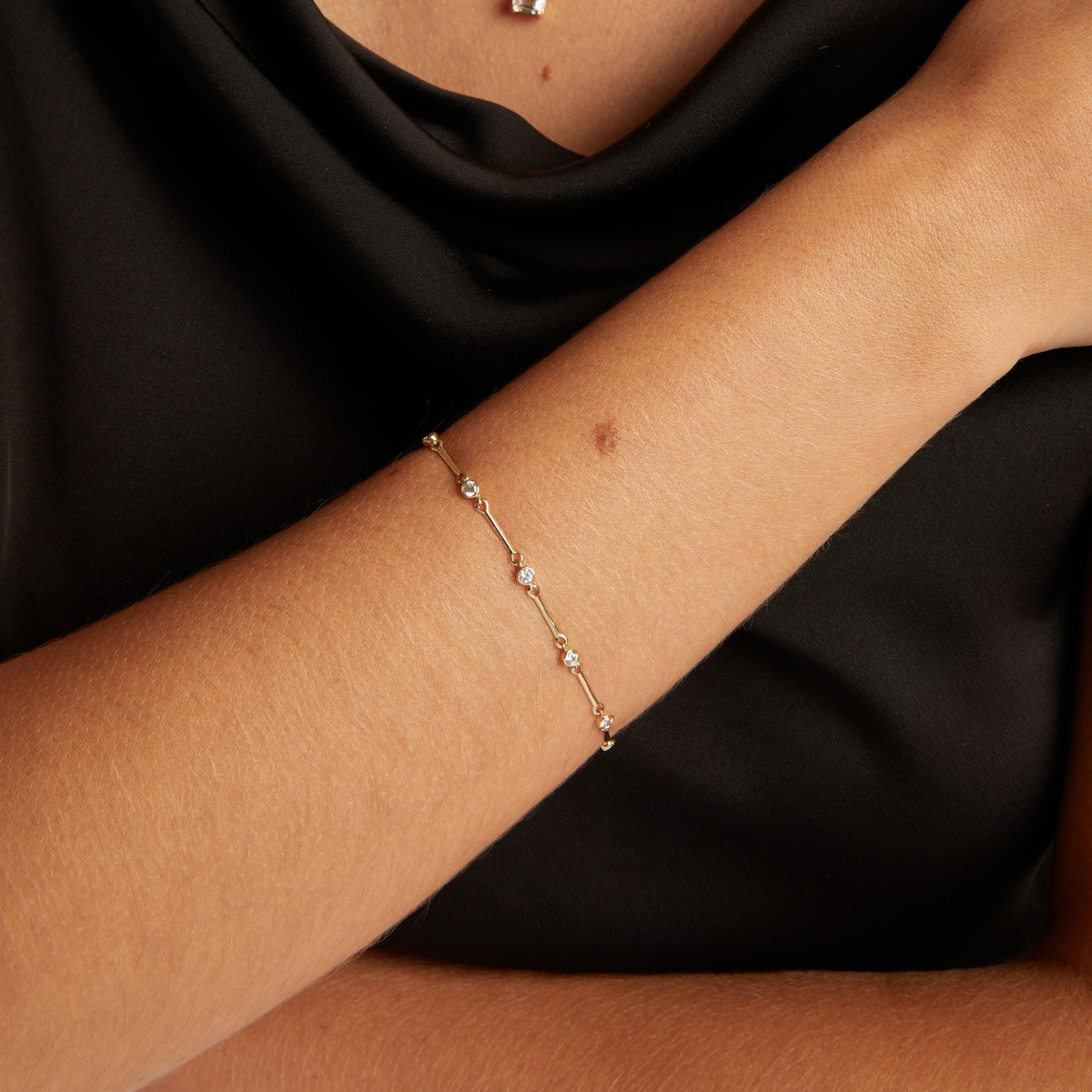 Model. Close up of woman's wrist with a diamond bar bracelet on black shirt. 