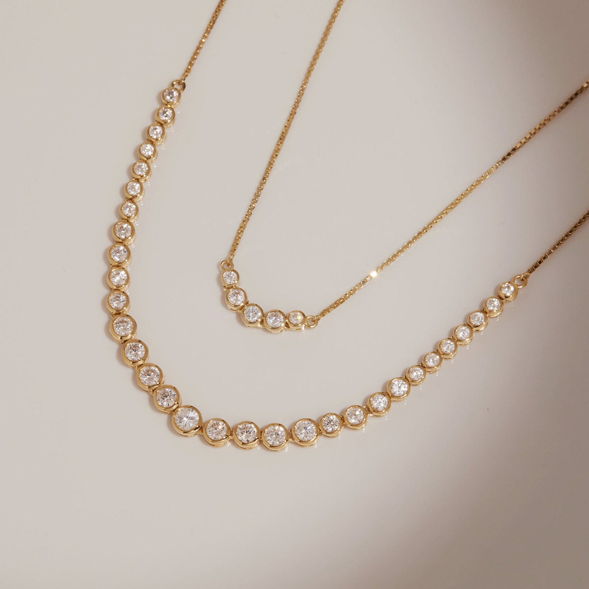 Flatlay Model two gold necklaces with diamonds laying flat 