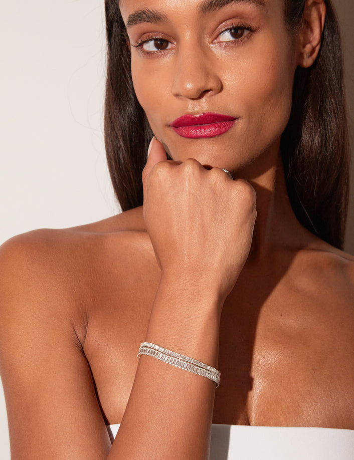 Close-up of a woman wearing stacked white sapphire tennis bracelets