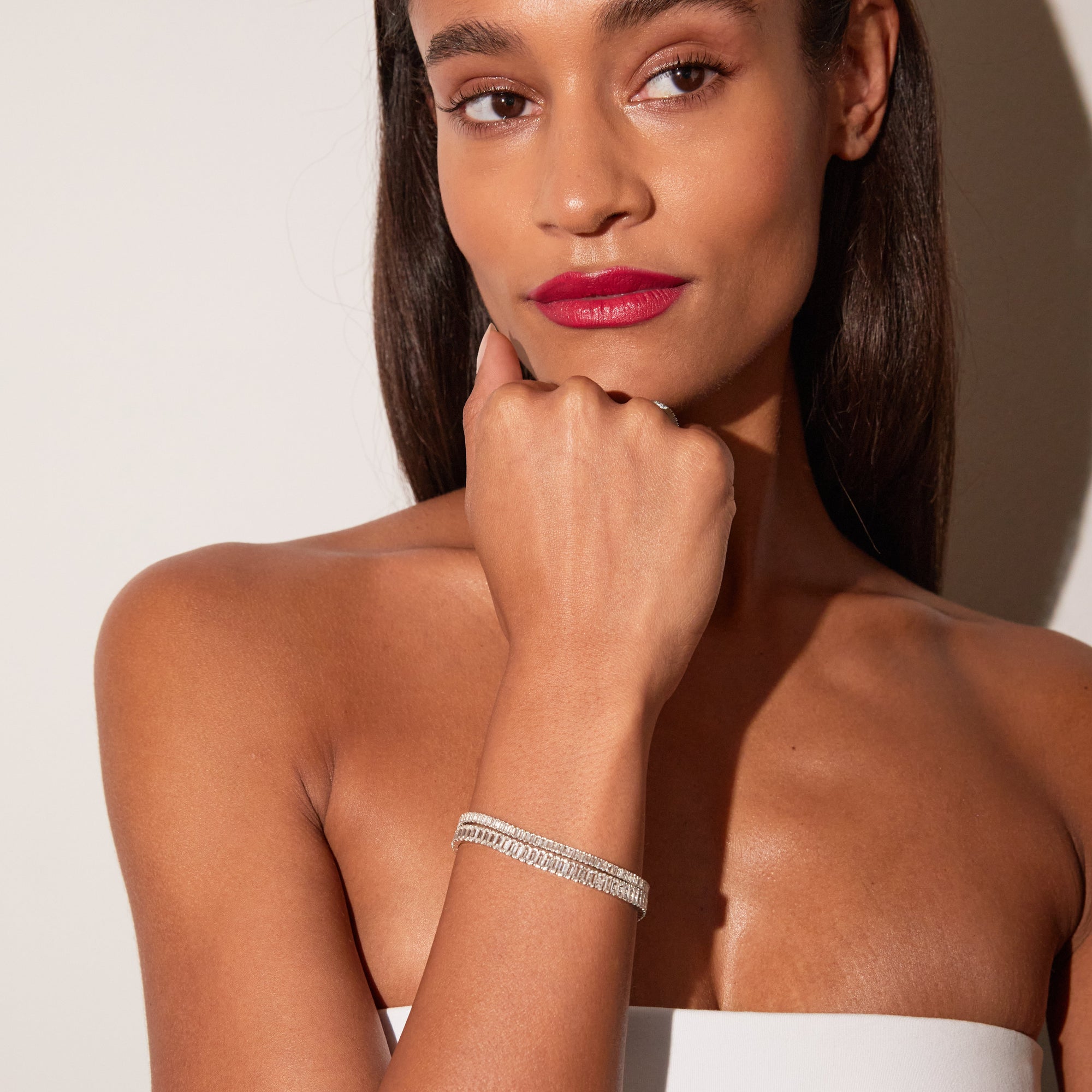 Close-up of a woman wearing stacked white sapphire tennis bracelets