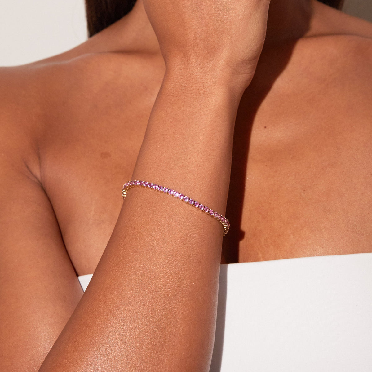 Model. Close up of a woman wearing a pink tennis bracelet 