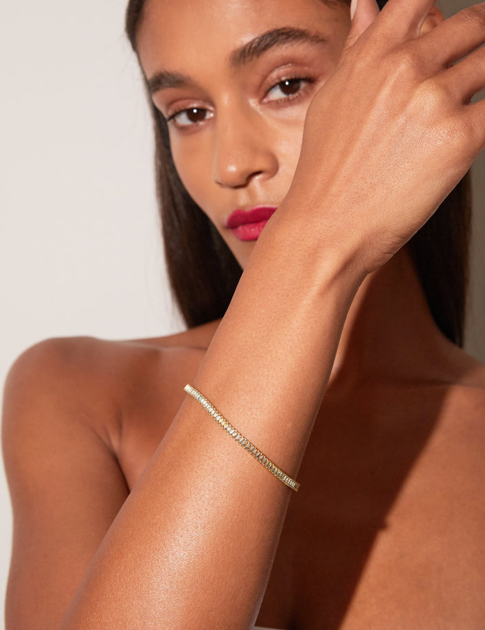 Woman wearing aquamarine tennis bracelet on neutral background