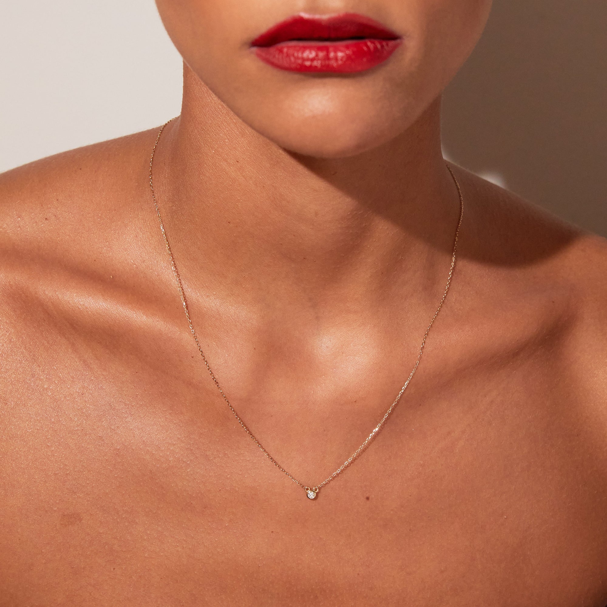 A close-up lifestyle shot of a woman wearing a delicate gold diamond necklace.