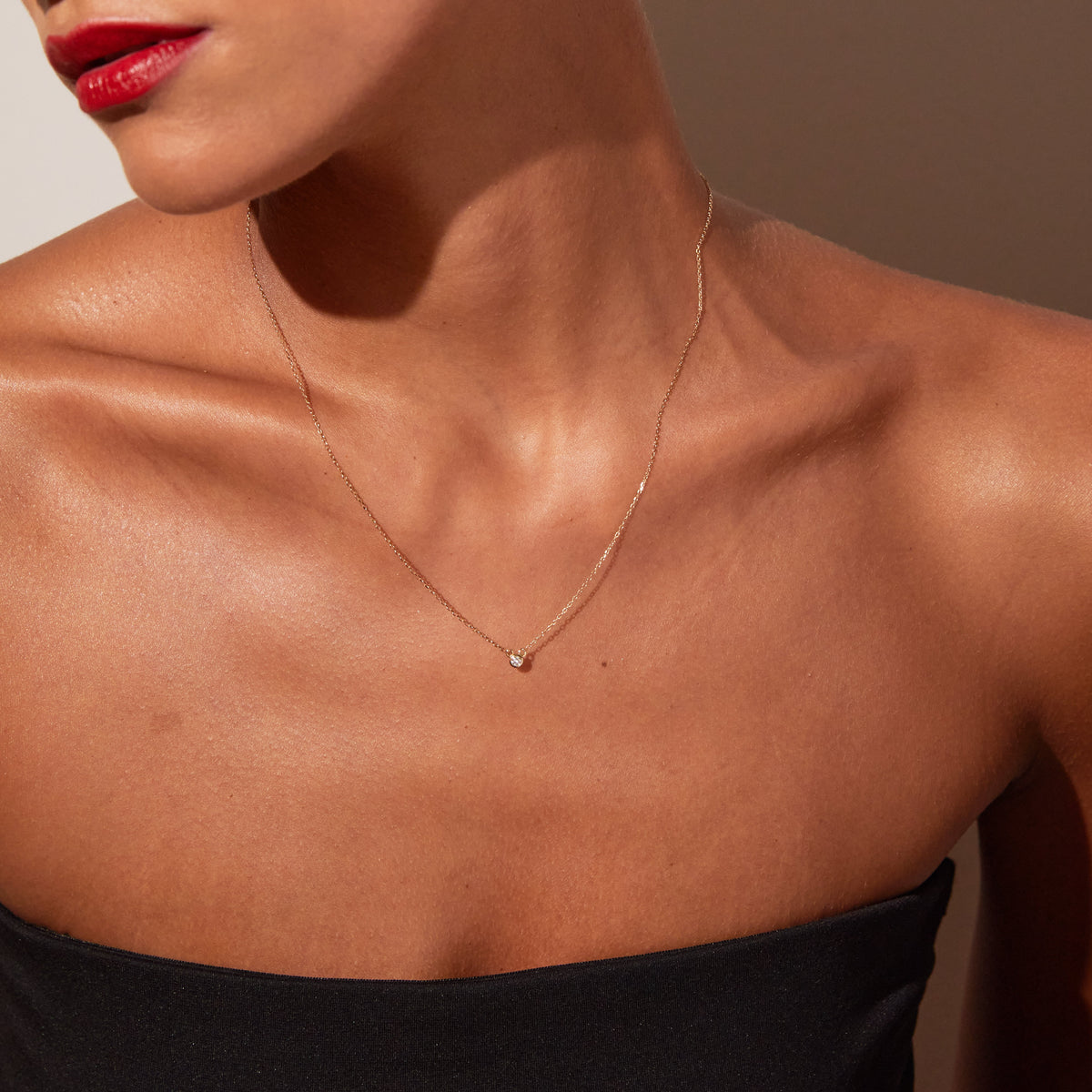 Model. A close-up lifestyle shot of a woman wearing a delicate gold diamond necklace.