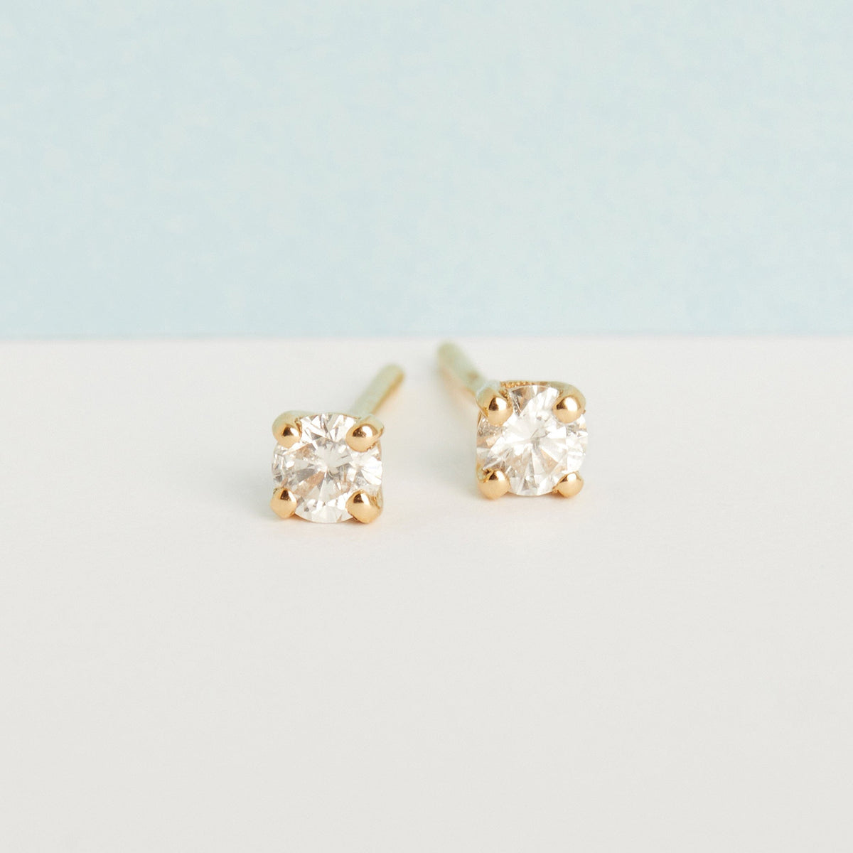 Flatlay Model two diamond stud earrings on plain background 