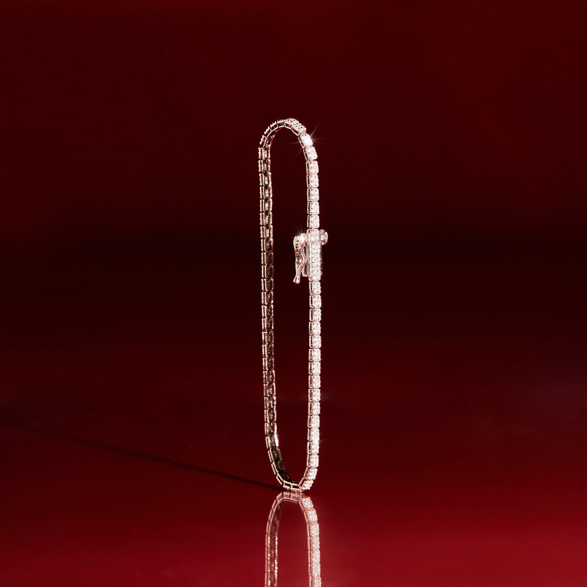 Flatlay Model A single diamond tennis bracelet displayed vertically against a dark red background.