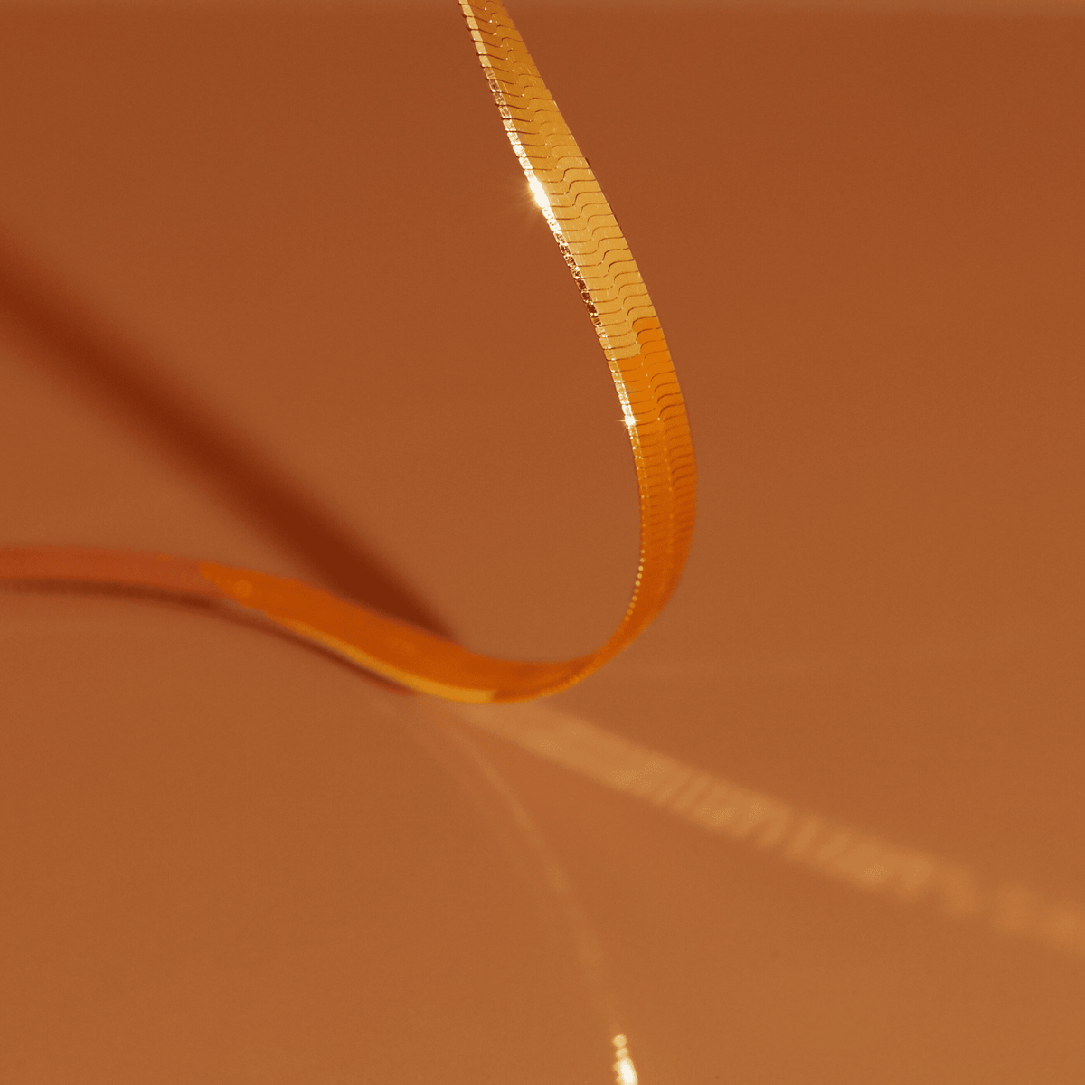 Flatlay Model. Close up of gold chain bracelet on orange background