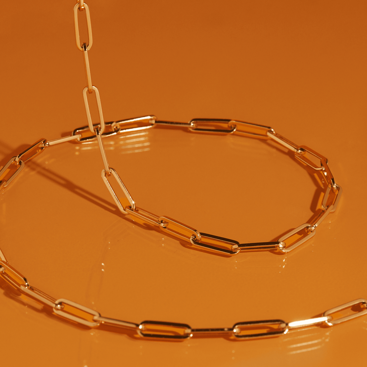 Flatlay Model. Close up of gold chain necklace on orange background