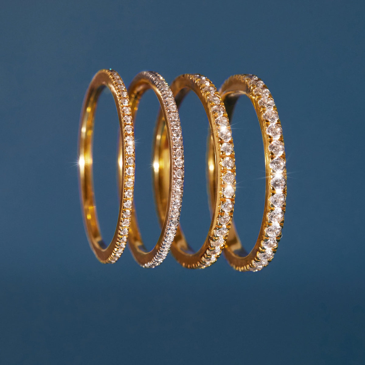 Flatlay Model four gold rings on a blue background 
