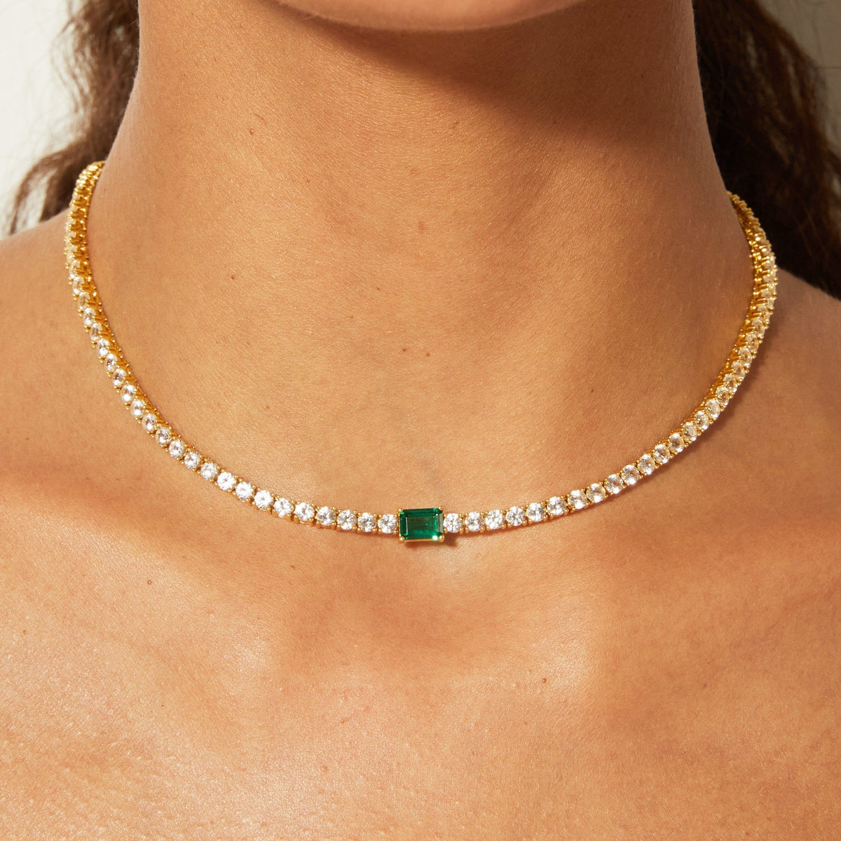 Lifestyle Model close up of woman wearing diamond necklace with an emerald 