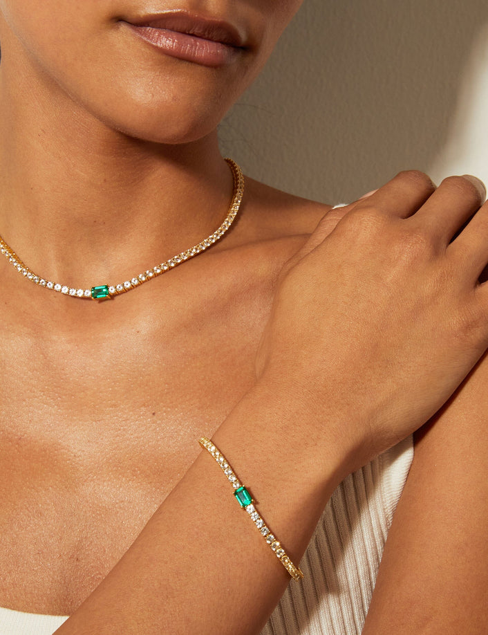 Lifestyle Model woman wearing diamond necklace with a green emerald and matching bracelet 
