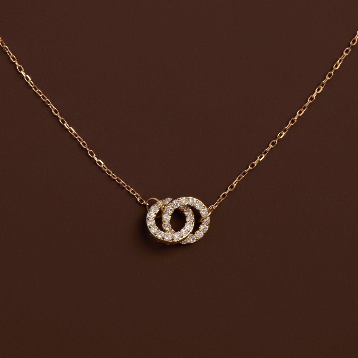 Model. Gold necklace with a diamond pendant on a brown background