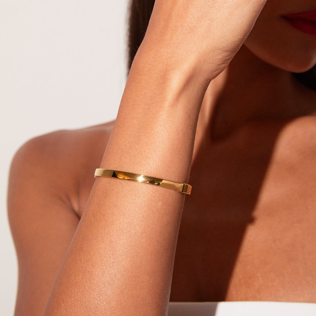 Model. Close up of a woman wearing a gold hinged bracelet