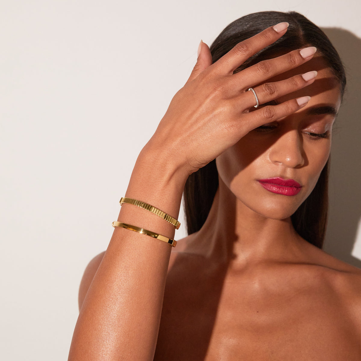 Model. Close up of a woman wearing two gold hinged bracelets