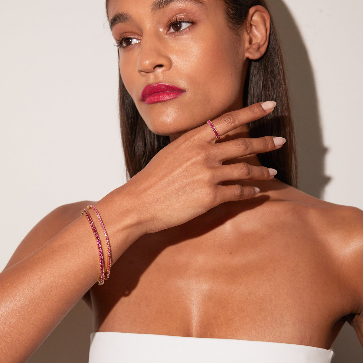 Model. Close up of a woman wearing two red tennis bracelets and a matching ring