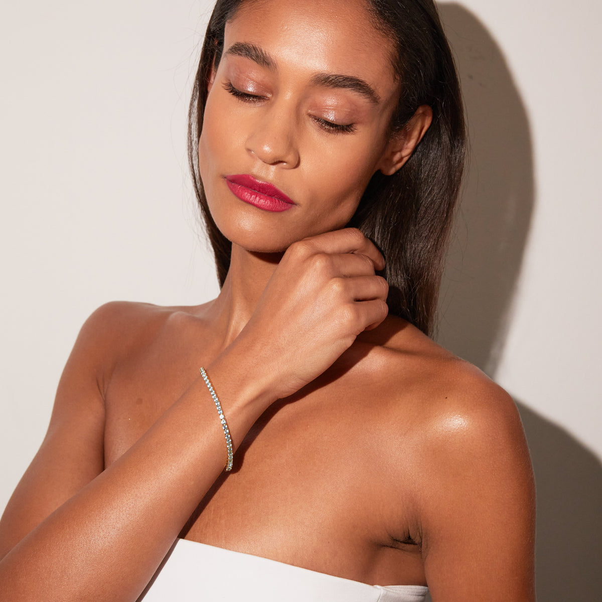 Model. Woman wearing blue tennis bracelet on neutral background