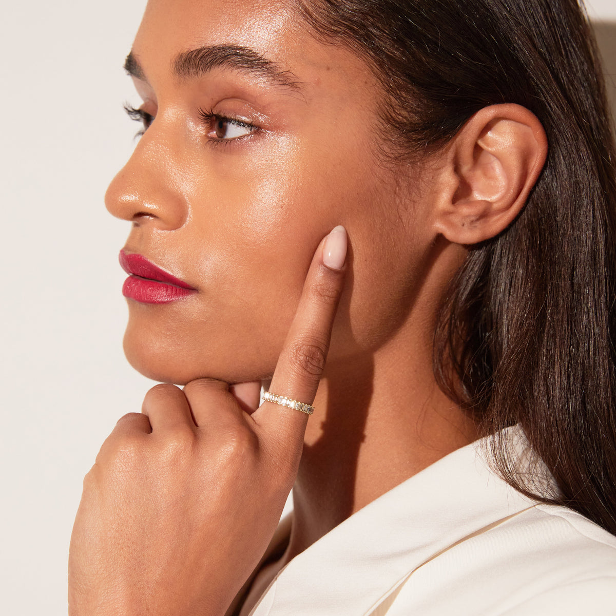 Model. Close-up of a woman with her hand near her face, wearing a ring.