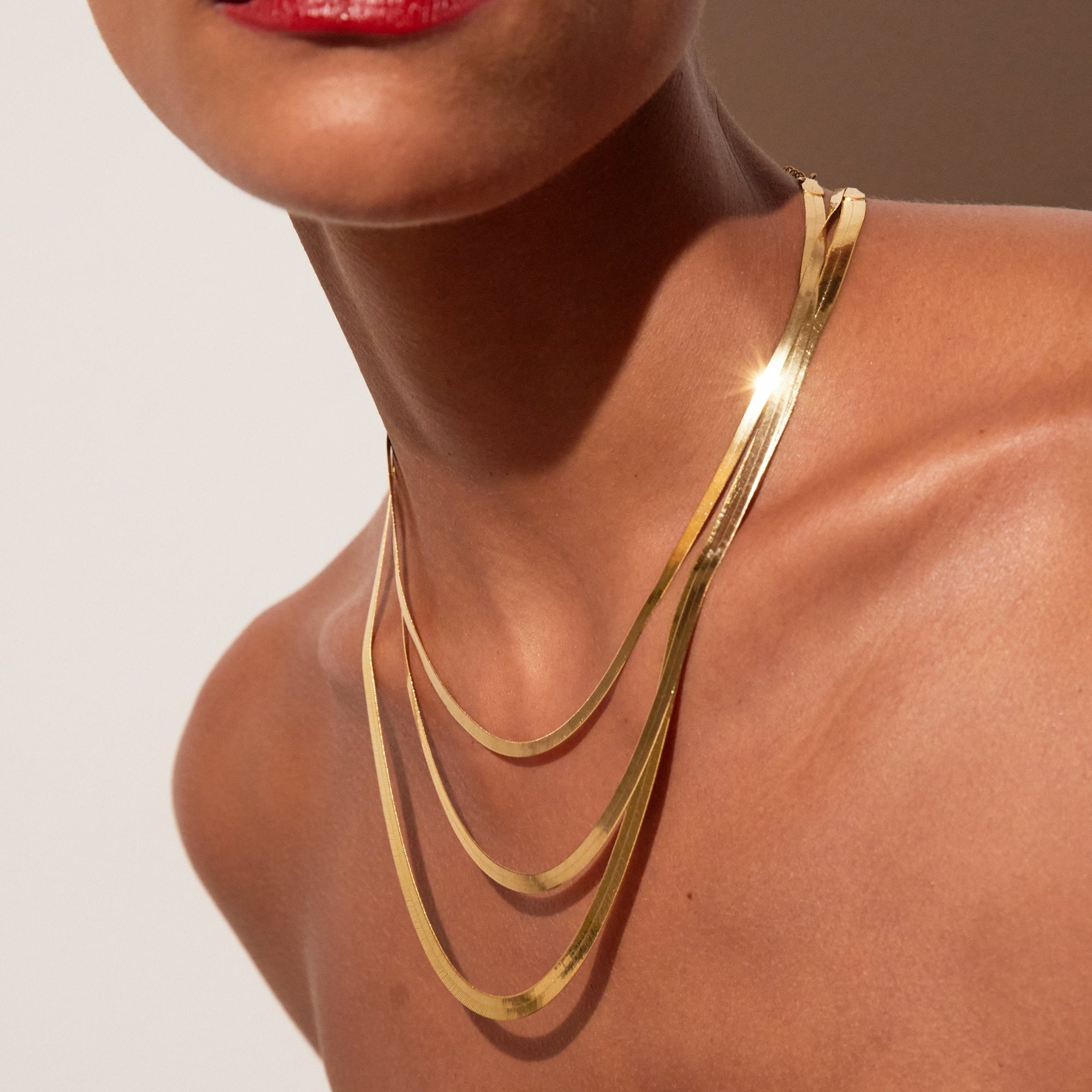 Close up of woman wearing three stacked gold chains 