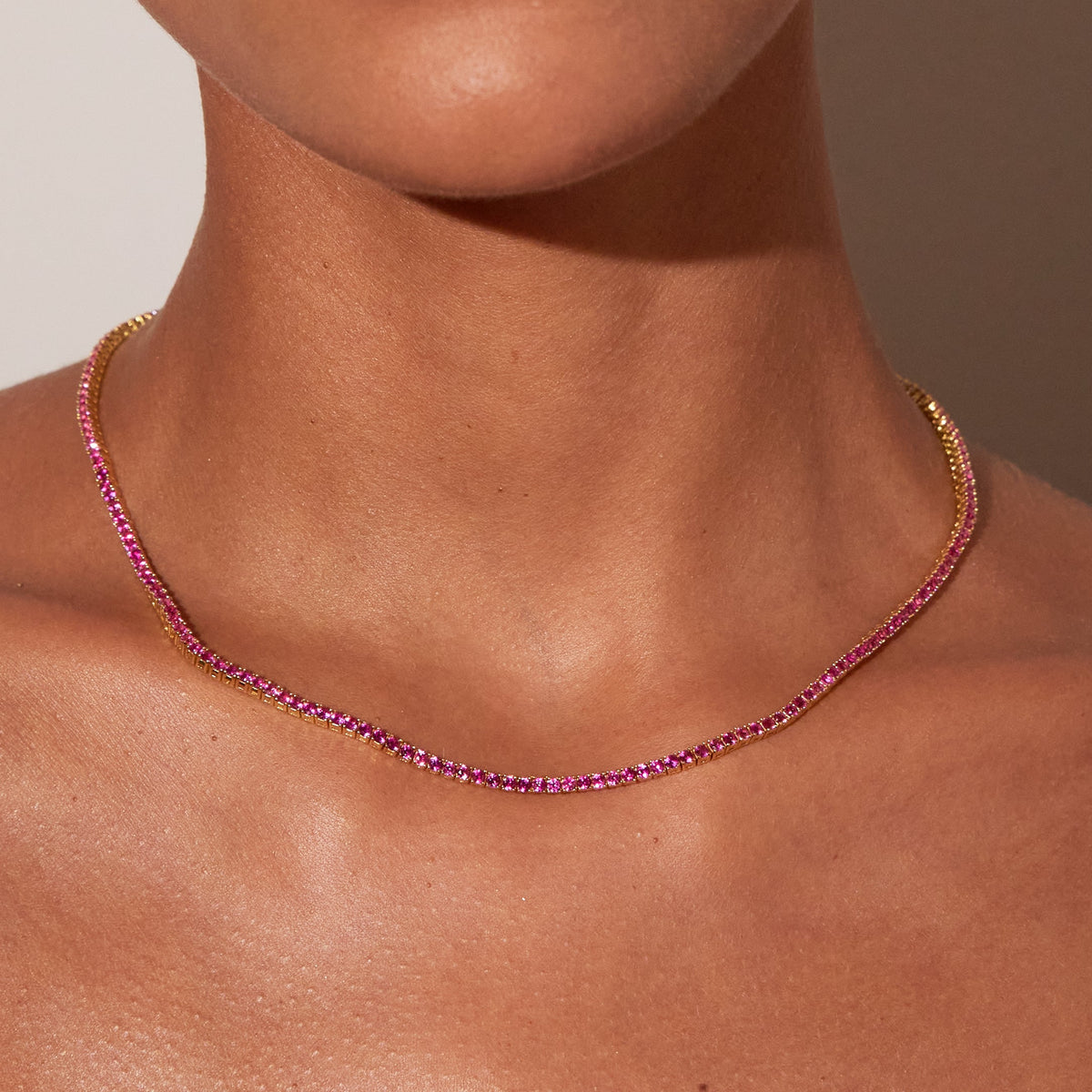 Model. Close up of a red tennis necklace on a woman's neck 