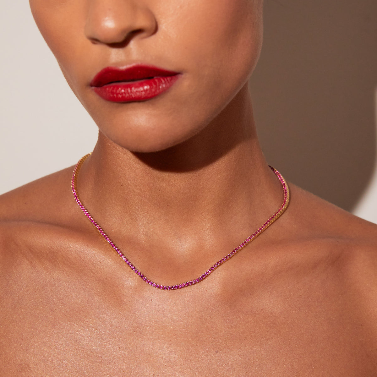 Model. Close up of a red tennis necklace on a woman's neck 