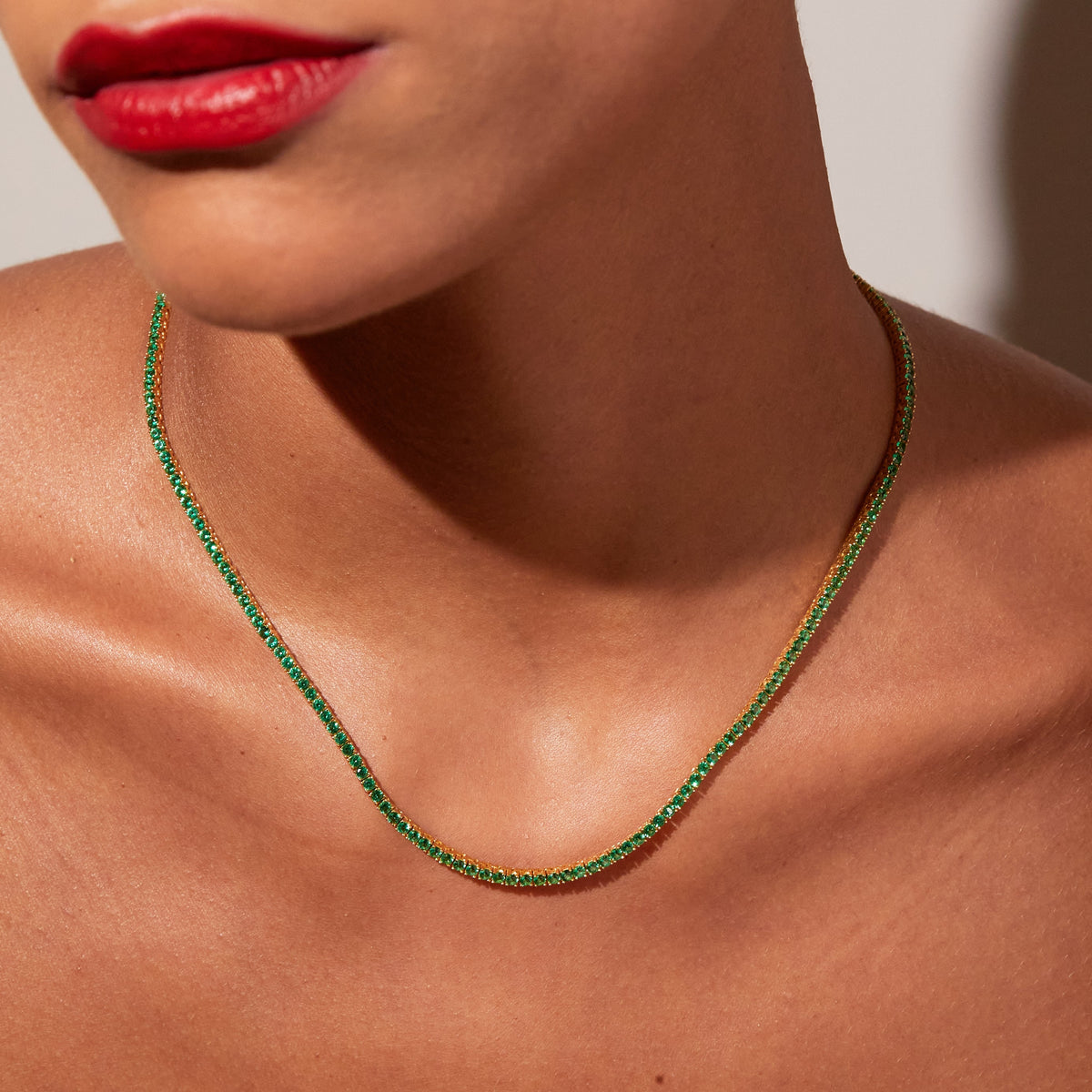 Model.  Close up of woman wearing green stone necklace 