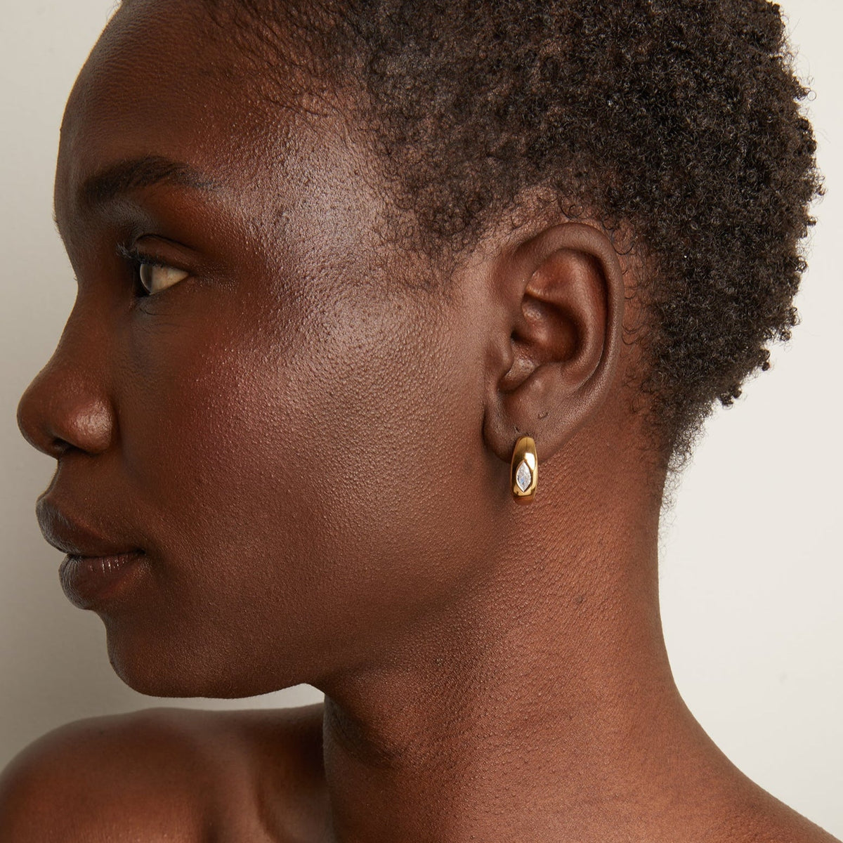Model woman wearing gold hoop earring 