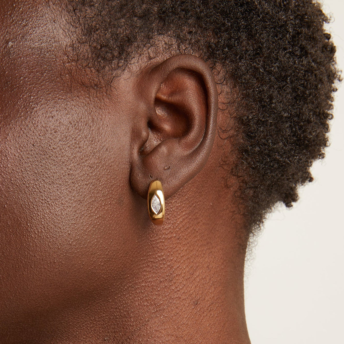 Model Close up of woman wearing gold hoop earring 