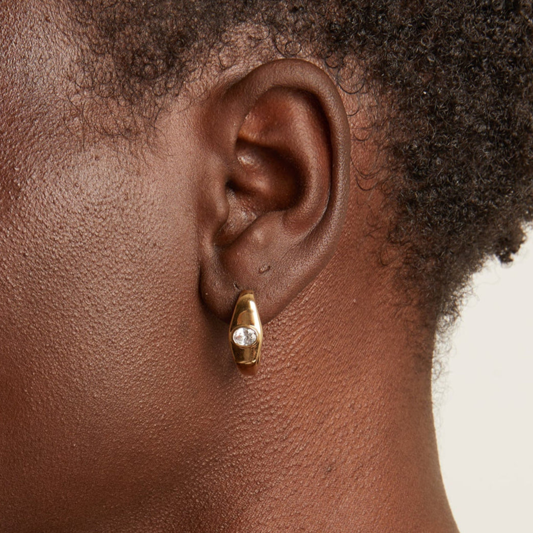 Model. Close up of woman wearing gold earring 