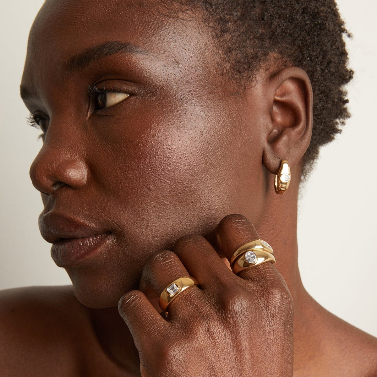 Model. Woman wearing rings and gold earring 